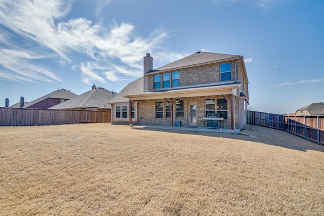 back of house featuring brick siding, a lawn, a chimney, and a fenced backyard