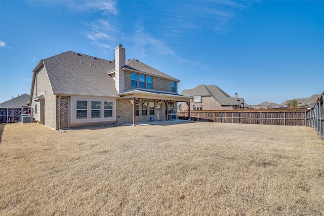 rear view of house featuring a patio, central AC unit, a fenced backyard, brick siding, and a yard