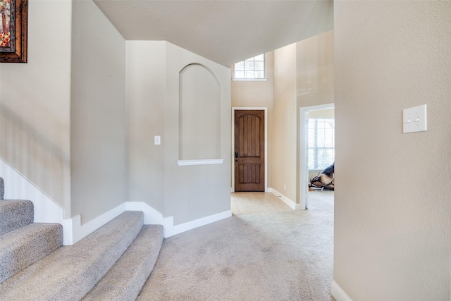 foyer with carpet floors, baseboards, a towering ceiling, and stairway