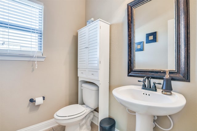 bathroom with a sink, toilet, and baseboards