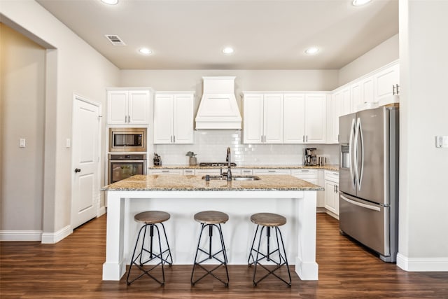 kitchen featuring stainless steel appliances, a sink, visible vents, white cabinets, and custom exhaust hood