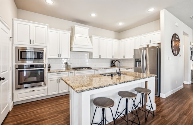 kitchen with premium range hood, appliances with stainless steel finishes, dark wood finished floors, and a sink