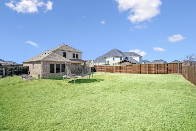 view of yard with a trampoline and a fenced backyard