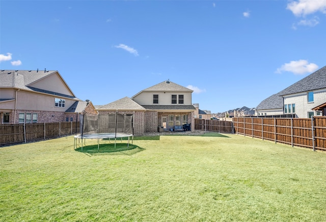 view of yard featuring a trampoline and a fenced backyard