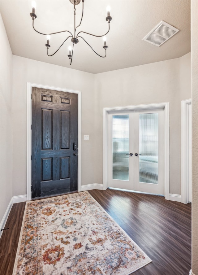 foyer entrance with dark wood-style floors, french doors, visible vents, a chandelier, and baseboards