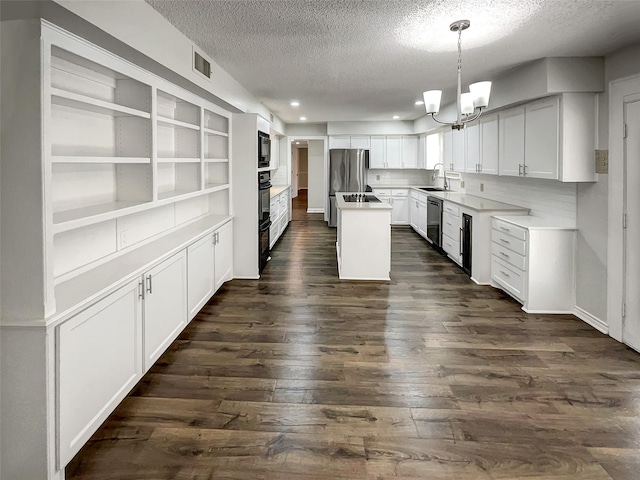 kitchen with a notable chandelier, a sink, a center island, dark wood-style floors, and black appliances