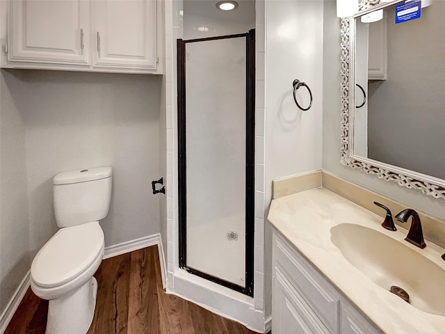 bathroom featuring toilet, a stall shower, baseboards, and wood finished floors