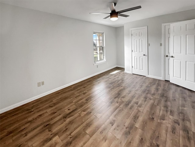 unfurnished bedroom with dark wood-style floors, baseboards, and a ceiling fan