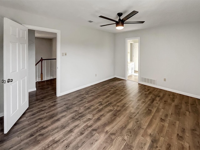 spare room with dark wood-style floors, visible vents, and baseboards