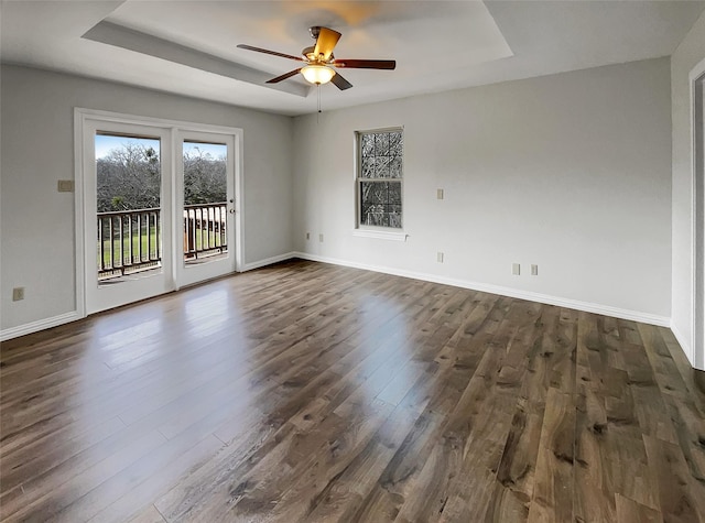 spare room featuring dark wood-style floors, baseboards, and a tray ceiling