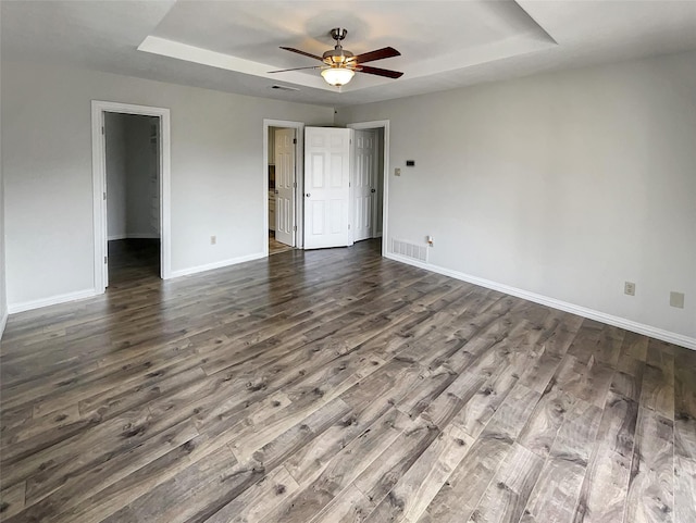 spare room with baseboards, visible vents, a raised ceiling, and dark wood-type flooring