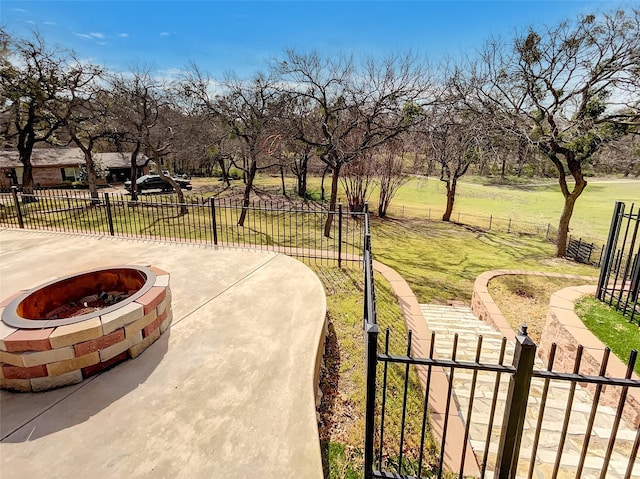 view of community featuring fence private yard, an outdoor fire pit, a gate, and a lawn