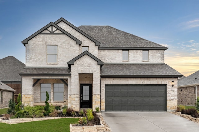 view of front facade featuring a garage, a shingled roof, concrete driveway, and brick siding