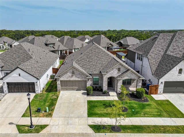 view of front of home with a shingled roof, an attached garage, a front yard, a residential view, and driveway