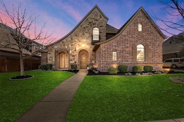 view of front of property featuring brick siding, stone siding, a yard, and fence