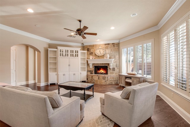 living room with baseboards, a fireplace, arched walkways, and ornamental molding