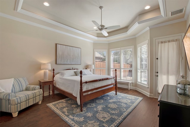 bedroom featuring visible vents, a raised ceiling, dark wood-type flooring, and ornamental molding