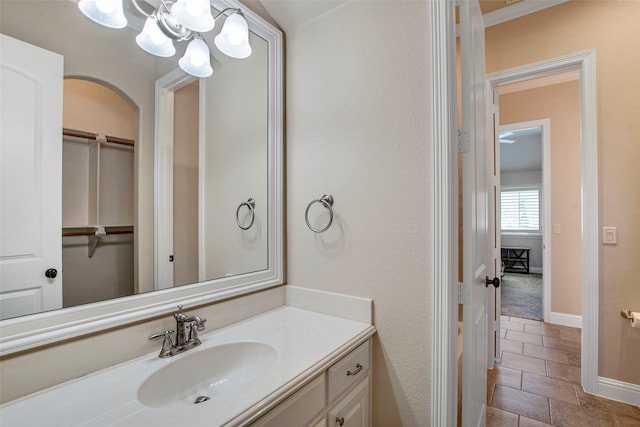 bathroom with a notable chandelier, vanity, and baseboards