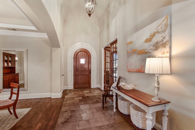 entryway featuring wood finished floors, a notable chandelier, arched walkways, and baseboards