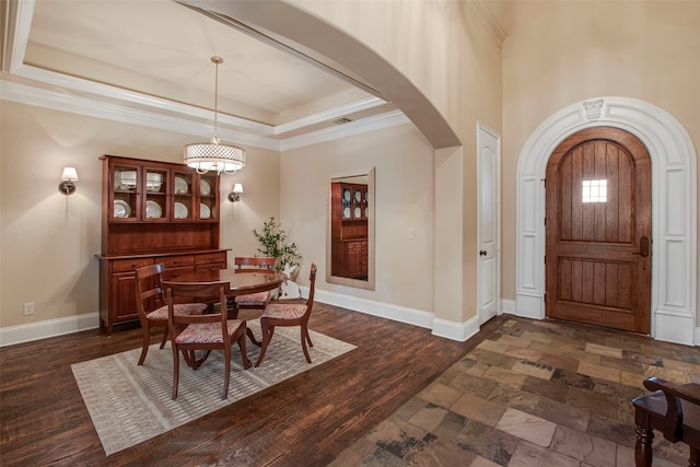 entryway with a raised ceiling, dark wood finished floors, arched walkways, crown molding, and baseboards