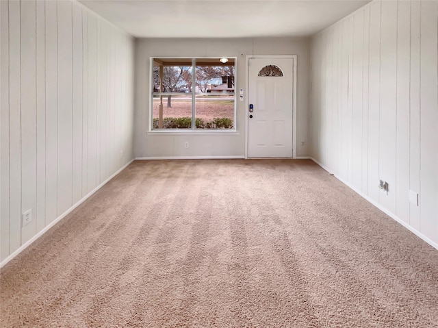 unfurnished room with carpet floors, wooden walls, and baseboards