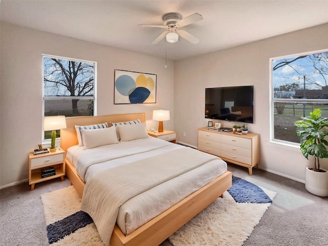 bedroom with light colored carpet, ceiling fan, and baseboards