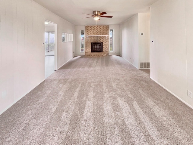 unfurnished living room with ceiling fan, carpet floors, a fireplace, and visible vents