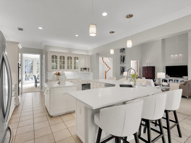 kitchen featuring a kitchen bar, crown molding, a large island with sink, and a sink