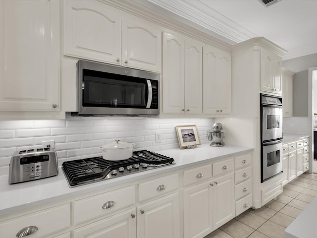 kitchen with light tile patterned floors, white cabinets, appliances with stainless steel finishes, and light countertops