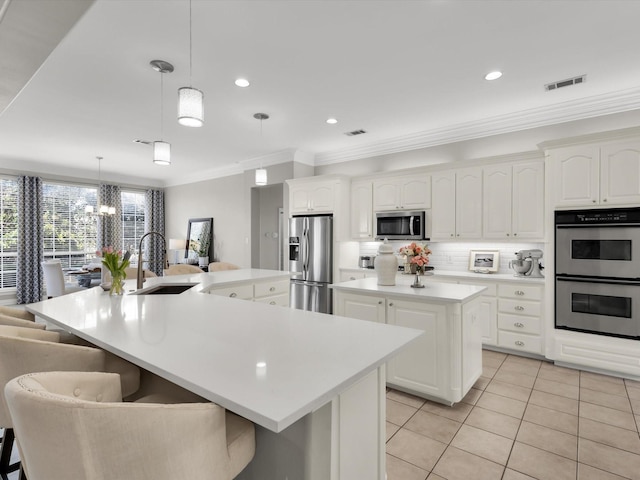 kitchen with visible vents, backsplash, a large island with sink, appliances with stainless steel finishes, and a sink