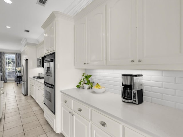 kitchen with decorative backsplash, appliances with stainless steel finishes, white cabinets, and light countertops