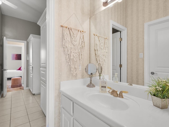 bathroom featuring vanity, baseboards, wallpapered walls, ceiling fan, and tile patterned flooring