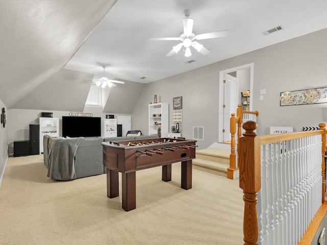 playroom featuring a ceiling fan, vaulted ceiling, light colored carpet, and visible vents