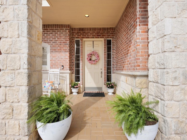 property entrance featuring stone siding, brick siding, and covered porch