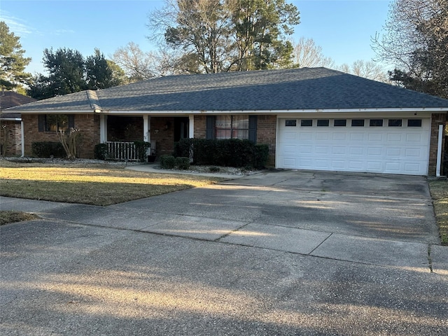 ranch-style house with driveway, roof with shingles, a garage, and brick siding