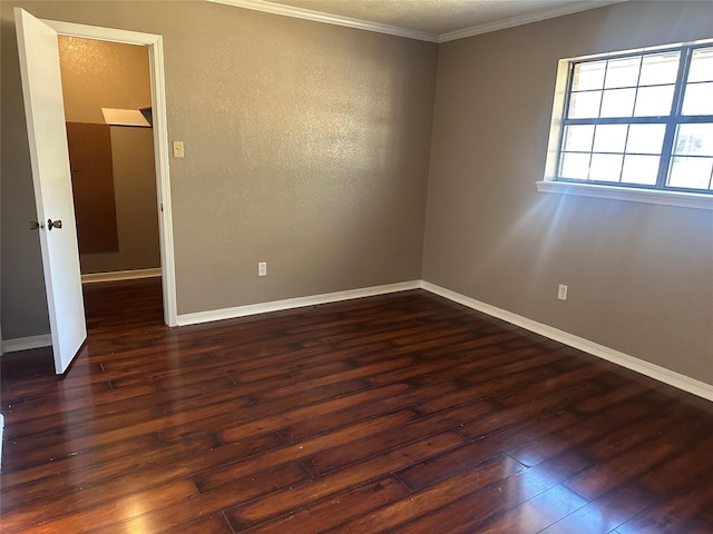 unfurnished room with dark wood-style floors, crown molding, and baseboards