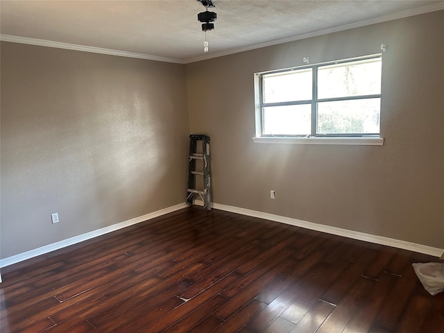 empty room featuring ornamental molding, dark wood-style flooring, a textured ceiling, and baseboards