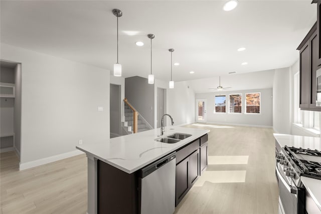 kitchen featuring light stone counters, recessed lighting, stainless steel appliances, a sink, and light wood finished floors