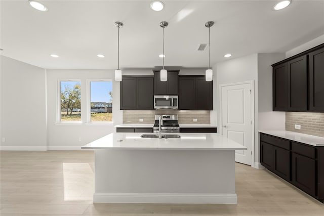 kitchen featuring visible vents, light wood-style flooring, stainless steel appliances, light countertops, and a sink