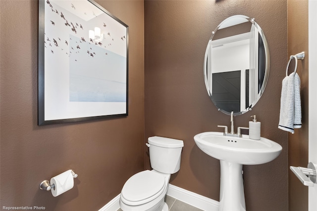 half bath with toilet, tile patterned flooring, and baseboards