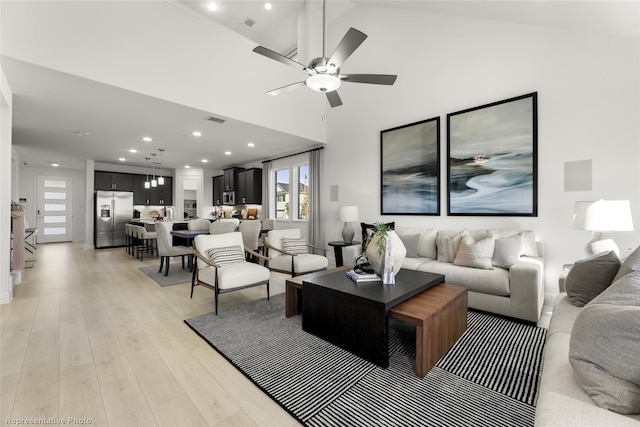 living area featuring recessed lighting, a towering ceiling, visible vents, a ceiling fan, and light wood finished floors