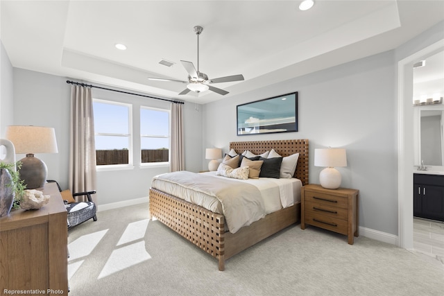 bedroom with a raised ceiling, light carpet, a sink, and baseboards