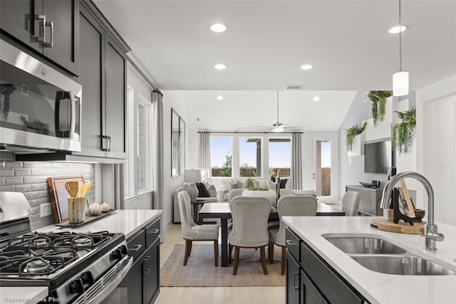 kitchen featuring visible vents, open floor plan, a sink, stainless steel appliances, and backsplash