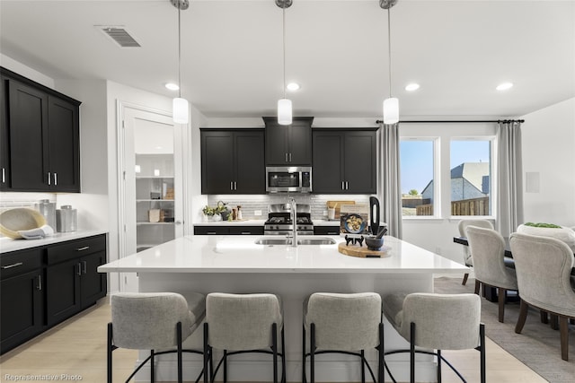 kitchen with appliances with stainless steel finishes, a kitchen breakfast bar, and dark cabinetry