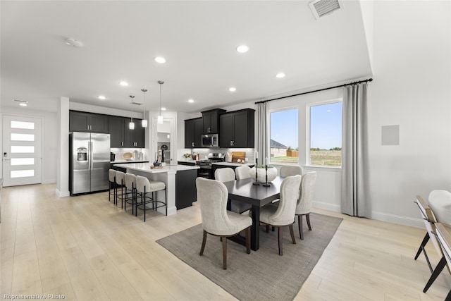 dining space featuring light wood finished floors, baseboards, visible vents, and recessed lighting