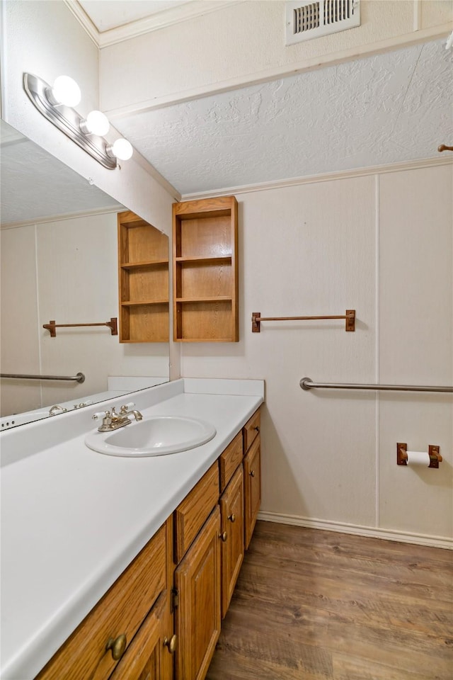 bathroom featuring vanity, wood finished floors, visible vents, and crown molding