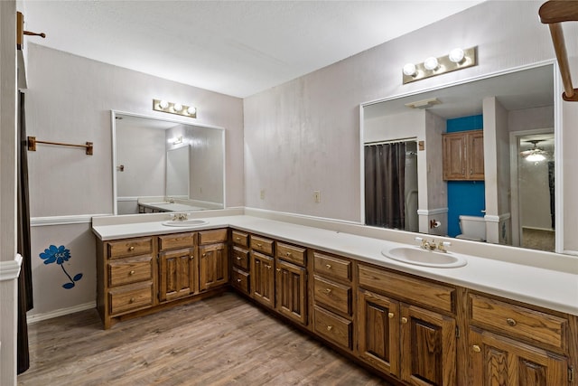 full bathroom with double vanity, wood finished floors, a sink, and toilet