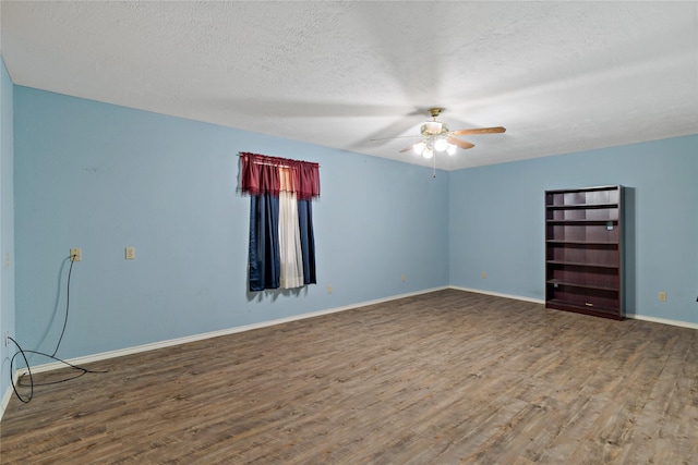 unfurnished room with ceiling fan, a textured ceiling, baseboards, and wood finished floors