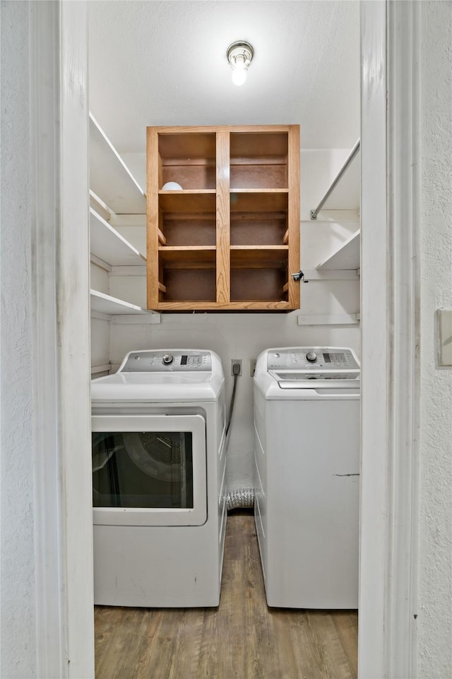 laundry room featuring wood finished floors, laundry area, and separate washer and dryer