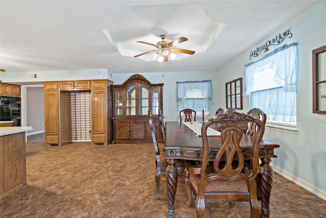 dining space featuring visible vents, a tray ceiling, a ceiling fan, and baseboards